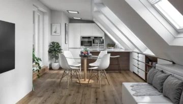 Bright attic kitchen-dining area with skylight, Eames chairs, and built-in storage beneath sloped ceiling