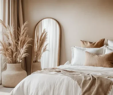 A warm minimalist bedroom with a mirror leaning on the wall, bed adorned with soft linens and decorative pillows featuring neutral tones and natural textures.