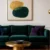Luxury jewel tone interior design featuring emerald green velvet sofa with gold coffee table, abstract art, and purple accent pillows
