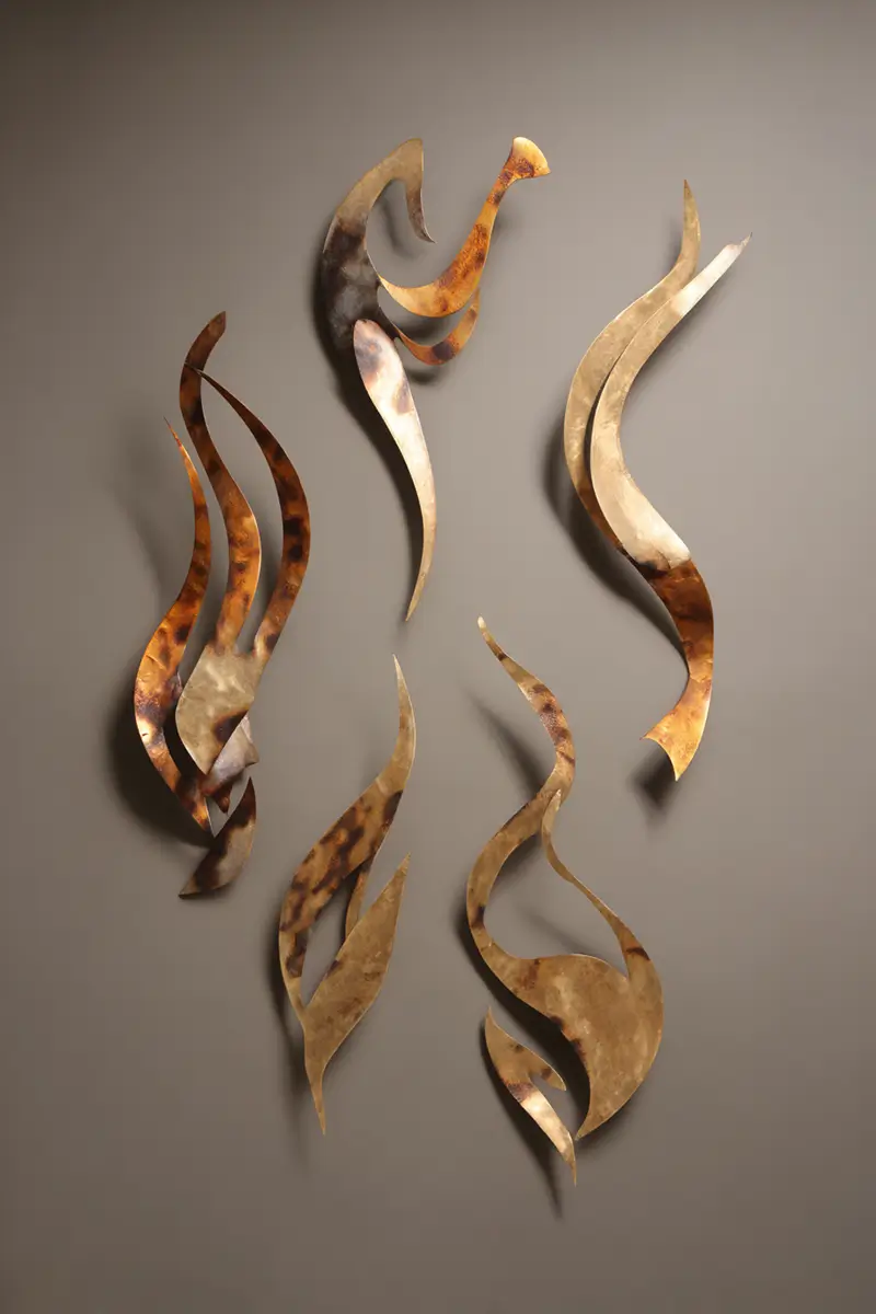 Abstract bronze metal sculptures with flowing organic forms mounted on neutral wall, suggesting movement and natural elements