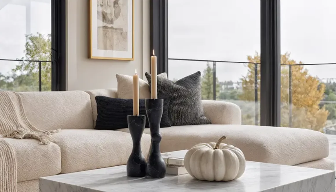 Minimalist Halloween decorations in a living room with black taper candles, white ceramic pumpkin, and neutral sofa - sophisticated seasonal decorating without visual overwhelm