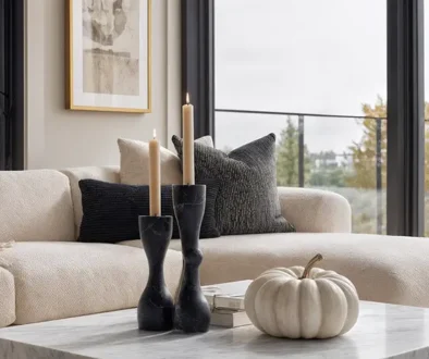 Minimalist Halloween decorations in a living room with black taper candles, white ceramic pumpkin, and neutral sofa - sophisticated seasonal decorating without visual overwhelm
